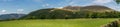 A panoramic view of mountains with a forest and fields.