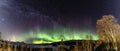 Panoramic view of multicolored spiky Aurora curved above Scandinavian mountains and frozen lake, very cold winter night, deep