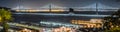 Panoramic view of the night illuminated Bay Bridge connecting San Francisco and Oakland; Ferry terminals and ptehr piers in the Royalty Free Stock Photo