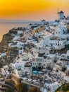Panoramic view of Oia village with traditional white architecture and windmills in Santorini island in Aegean sea at sunset, Royalty Free Stock Photo
