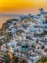 Panoramic view of Oia village with traditional white architecture and windmills in Santorini island in Aegean sea at sunset, Royalty Free Stock Photo