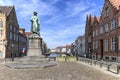 Panoramic view of the old streets of Bruges with a statue of Jan Van Eyck, a famous Flemish artist, on foreground