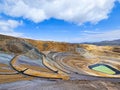 Panoramic view of an open pit mine with a lagoon in the background and sunny weather