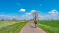 Panoramic view over countryside landscape and lonely cyclist cycling at cycling lane at sunny Spring day and blue sky. Concept