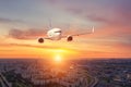 Panoramic view over the evening city during sunset, and a flying passenger plane