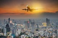 Panoramic view over the evening city during sunset, and White passenger plane flying in the sky above a city Royalty Free Stock Photo