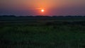 Panoramic view over the grassland between the dike and the beach against the deep setting sun on the North Sea coast. Royalty Free Stock Photo