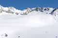 Panoramic view over a snowy slope with hikers