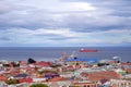 Panoramic view of Punta Arenas, showing colorful roofs, against the ocean covered by a dramatic sky.