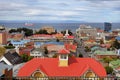 Panoramic view of Punta Arenas, showing colorful roofs, against the ocean covered by a dramatic sky.