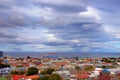 Panoramic view of Punta Arenas, showing colorful roofs, against the ocean covered by a dramatic sky.
