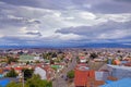 Panoramic view of Punta Arenas, showing colorful roofs, against the ocean covered by a dramatic sky.