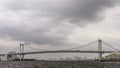 Panoramic view of the Rainbow Bridge in Tokyo, Japan, on a rainy day with cloudy sky