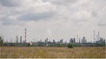 Panoramic view of the refinery with high striped pipes and yellow autumn field