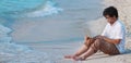 Panoramic view of relaxed young Asian man with computer laptop on the sandy beach in summer time. Summer vacations and lifestyle