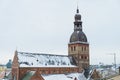 Panoramic view of Riga Cathedral featuring brick church structure clock tower and snow topped roofs Royalty Free Stock Photo