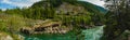 Panoramic view of a river in Montana wilderness with a cable bridge over water