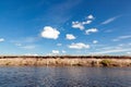 Panoramic view of riverbank with reflections of white fluffy clo