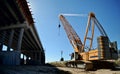 A panoramic view of a road overpass under construction and a yellow crawler crane in the morning sun