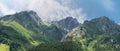 Panoramic view of row of mountains and forest with a blue sky and couds.