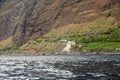 Panoramic view of sheer volcanic cliff rising above ocean.