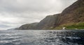 Panoramic view of sheer volcanic cliff rising above ocean.