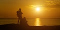 A panoramic view of the silhouette of men and women looking at the serene sunset