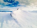 Panoramic view of a snow capped mountain peak with clouds and blue skies.