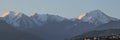 Panoramic view of the snow-capped mountain peaks of the Trans-Ili Alatau over several houses.