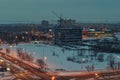 Panoramic view of a snow-covered hotel complex under construction and a shopping center in the evening twilight.