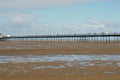 Panoramic view of southport pier from the beach with blue shy reflected in water on the beach at low tide Royalty Free Stock Photo