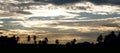 Panoramic view of sunset ray with clouds in sky and silhouette of landscape foreground Royalty Free Stock Photo