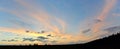 A panoramic view of the sunset sky and clouds, beautifully illuminated by the evening sun, the silhouette of several trees Royalty Free Stock Photo