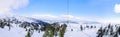 Panoramic view from top of the mountain to ski resort and chair lift going down. Winter vacation and sport travel concept. Selecti Royalty Free Stock Photo
