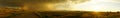 Panoramic view of a trail in a green fenced field in Montana during a thunderstorm