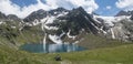 Panoramic view of turquoise blue mountain lake Grunausee in alpine landscape with green meadow and snow-capped mountain Royalty Free Stock Photo