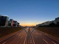 Panoramic view of two ways road between buildings at sunset