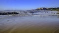 Panoramic view of a wavy ocean shore with urban settling on the background