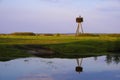 Panoramic view of wetlands covered with early spring green grass, woods and nesting White Stork in Biebrza River wildlife refuge