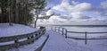 Panoramic view of wooden bench and Baltic sea coast covered in snow during sunny day with blue sky and clouds. Covered in snow sea Royalty Free Stock Photo