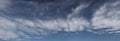 Sweeping panorama of soft wind swept clouds in blue sky.