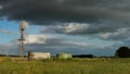 Panoramic of a water wind mill next to a large water storage tank on an agricultural sheep stock farm in rural Victoria with dark Royalty Free Stock Photo