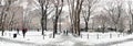 Panoramic winter scene with people walking through the snow covered landscape of Washington Square Park in New York City