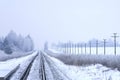 Panoramic winter view of a single-track snow-covered railroad going off into the distance.