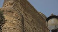 Panormama with a street lamp on the walls of an ancient stone tower.