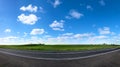 Panotama of green meadow with asphalt road and blue sky Royalty Free Stock Photo