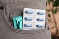 Pants with pills and condom in pocket, closeup. Potency problem Royalty Free Stock Photo