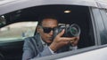 Paparazzi man sitting inside car and photographing with dslr camera Royalty Free Stock Photo