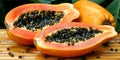 Papaya, with chopped pieces and black seeds, against the background of lush tropical veget