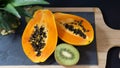 The papaya is cut into two halves, the stand is a stone board with a wooden frame Royalty Free Stock Photo